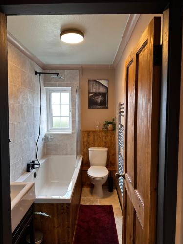 a bathroom with a tub and a toilet and a sink at The Hideaway in Stratford-upon-Avon