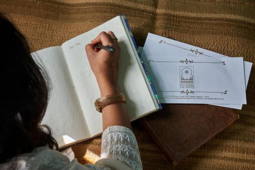 a woman is writing in a book with a pen at Kaladwas Lal Haveli - A Heritage Boutique Hotel in Udaipur