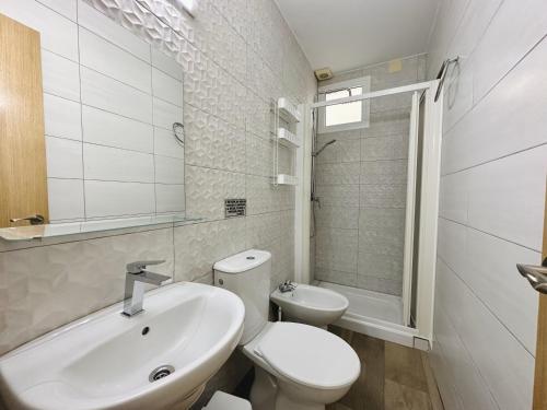 a white bathroom with a toilet and a sink at Apartamentos Turísticos Santo Rostro in Chipiona