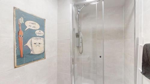 a shower in a bathroom with a picture of a carrot at A Prestwich Apartments M25 in Manchester
