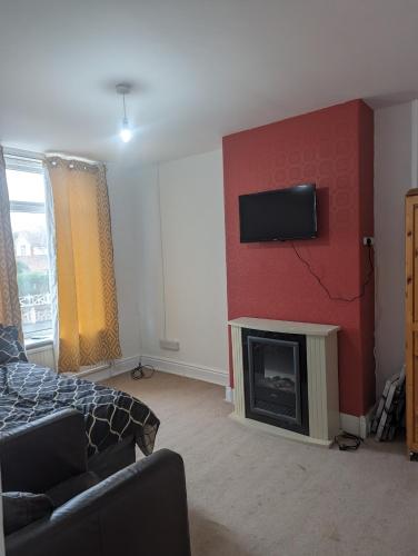 a living room with a fireplace and a tv on the wall at Little Guesthouse in Cleveleys