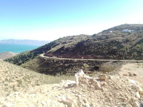 a winding road on a hill next to the ocean at Casa de campo in Al Hoceïma