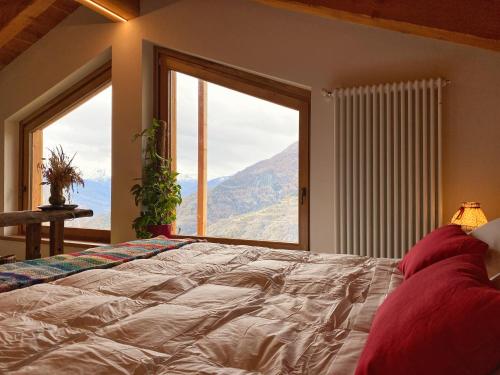 a bedroom with a large bed with a large window at Baita La Pesse - Ad un passo dalle stelle in Nus