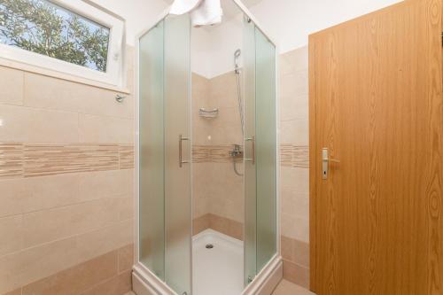 a shower with a glass door in a bathroom at Holiday Home Malačnica in Supetar