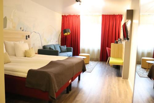 a hotel room with a large bed and a couch at ProfilHotels Calmar Stadshotell in Kalmar