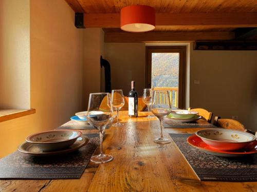 a wooden table with wine glasses and plates on it at Baita La Pesse - Ad un passo dalle stelle in Nus