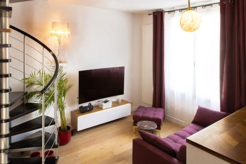 a living room with a purple couch and a tv at Joli Duplex Confort T2 Paris Porte De Versailles in Vanves