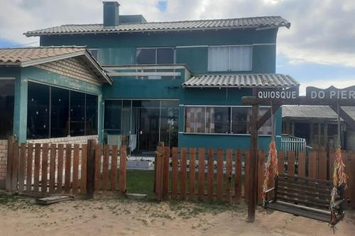 ein blaues Haus mit einem Holzzaun davor in der Unterkunft casa maravilhosa a Beira-Mar em Salinas in Cidreira