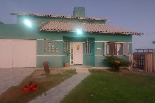 ein grünes Haus mit einer weißen Tür und einem Hof in der Unterkunft casa maravilhosa a Beira-Mar em Salinas in Cidreira