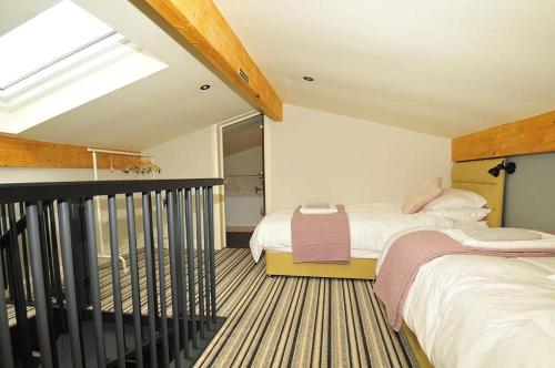 een slaapkamer op zolder met 2 bedden en een dakraam bij Westwood Lodge in Much Wenlock