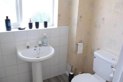 a bathroom with a sink and a toilet and a window at Coolfin House - London Excel in London