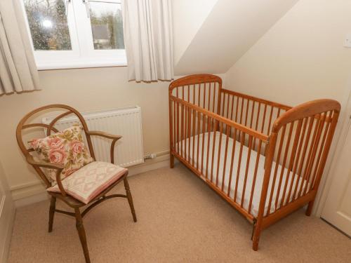 two cribs in a room with a chair and a window at 1 Cheriton Row in Carew