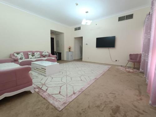 uma sala de estar com um sofá rosa e uma televisão de ecrã plano em 1 BHK fully furnished apartment em Dubai