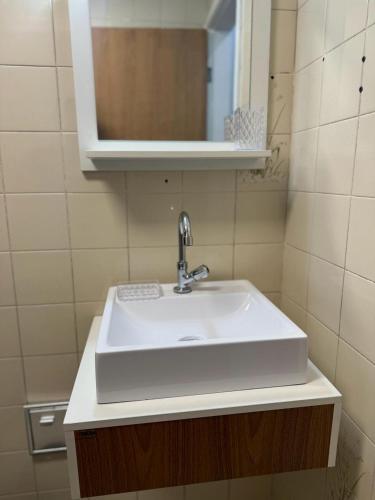 a white sink in a bathroom with a mirror at Apartamento em Praia Grande in Praia Grande