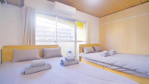 2 Betten in einem Zimmer mit Fenster in der Unterkunft CowCow Hotel Shinjuku in Tokio