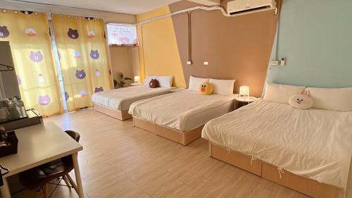 ein Hotelzimmer mit 2 Betten und einem Schreibtisch in der Unterkunft 逢甲菓子宿 in Taichung
