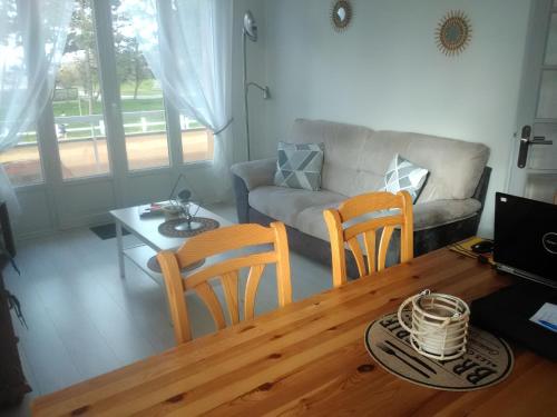 ein Wohnzimmer mit einem Tisch, Stühlen und einem Sofa in der Unterkunft Résidence de la plage in Ouistreham