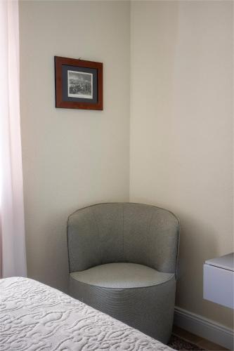a chair sitting in a corner of a bedroom at Villa Raggi Relais in Castelletto d'Orba