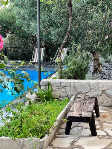 a wooden bench sitting in front of a pond at Great 4-bedroom villa w heated eco pool in Duće