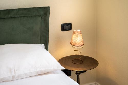a bed with a table and a lamp next to a bed at Villa Raggi Relais in Castelletto d'Orba