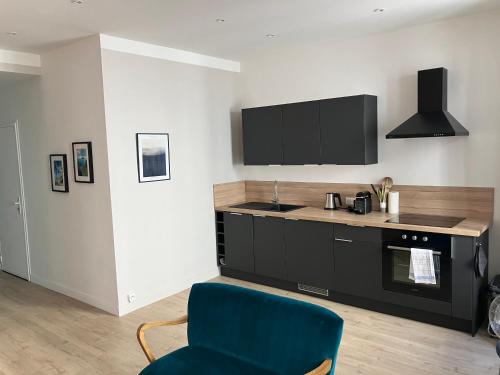 un salon avec une chaise bleue et une cuisine dans l'établissement Le Diffonty Cosy Vintage centre Historique, à La Ciotat