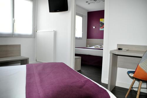 a bedroom with a purple bed and a desk at Logis hôtel restaurant la Haute Forêt in Vertou