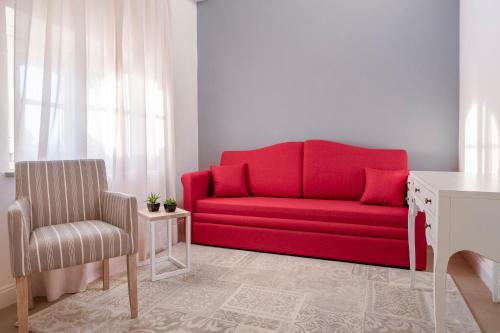 a red couch in a living room with a chair at Villa Raggi Relais in Castelletto d'Orba