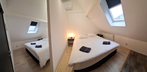 2 łóżka w małym pokoju z 2 oknami w obiekcie Huis ALNA 4 w mieście Mechelen