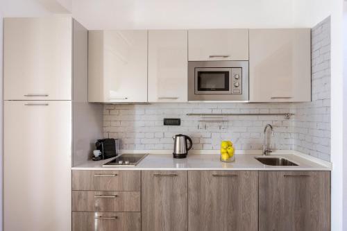 a kitchen with white cabinets and a sink and a microwave at Villa Raggi Relais in Castelletto d'Orba