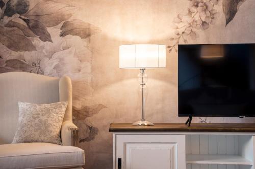 a living room with a tv and a chair and a lamp at Villa Raggi Relais in Castelletto d'Orba