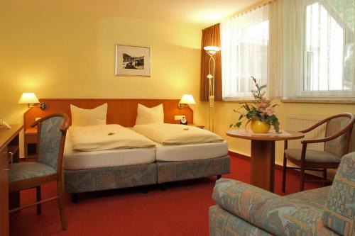 a bedroom with a bed and a table and chairs at Hotel Am Schlossberg in Ziegenrück