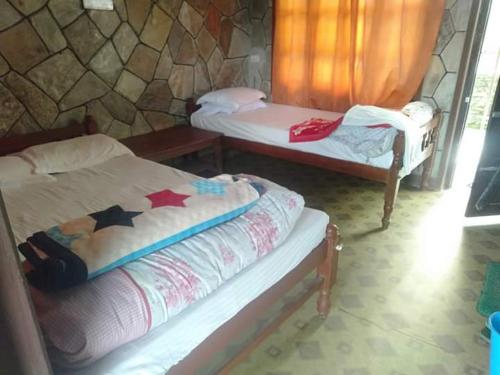 two beds in a room with a stone wall at The Hotel Orchid & Restaurant in Kāskī