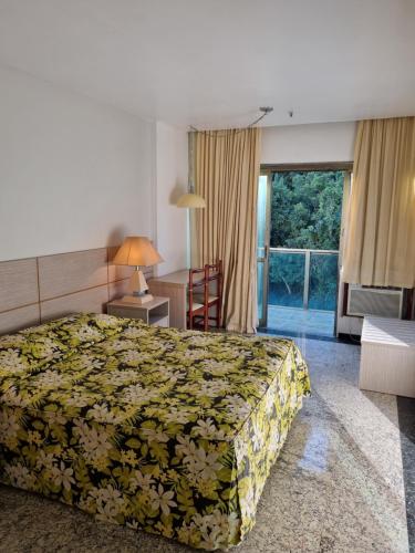 a hotel room with a bed and a desk and window at Royalty Copacabana Hotel in Rio de Janeiro