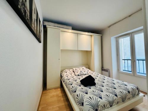 een kleine slaapkamer met een bed in een kamer bij Parisian Escape: Parc Monceau in Parijs