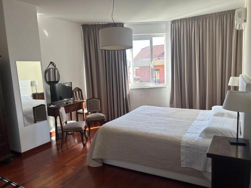 a bedroom with a bed and a desk and a window at RAMO FIORITO in Sant’Agata Li Battiati 