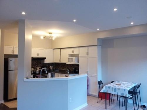 a kitchen with white cabinets and a table with chairs at 壹家民宿Basement1 in Markham