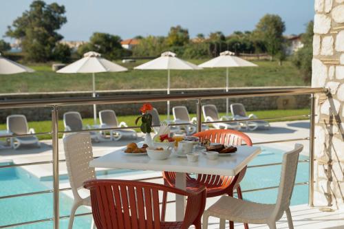 una mesa con comida en la parte superior de un balcón con sillas en Niriides Luxury Villas, en Methoni