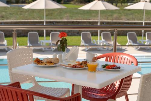 a white table with plates of food and orange juice at Niriides Luxury Villas in Methoni