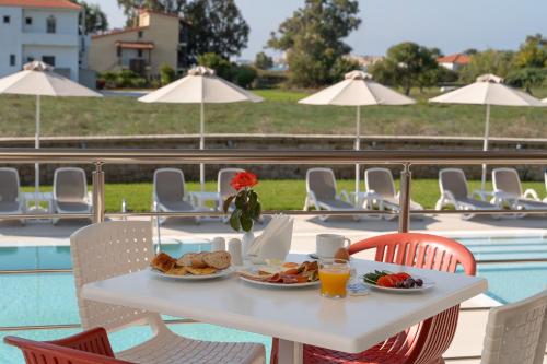 a white table with food on it next to a pool at Niriides Luxury Villas in Methoni