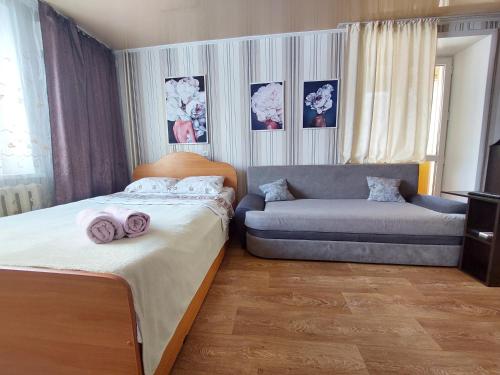 ein Schlafzimmer mit einem Bett und einem Sofa in der Unterkunft Комфортная квартира с удобным расположением in Līsakovsk