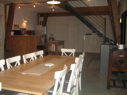 ein Esszimmer mit einem Holztisch und weißen Stühlen in der Unterkunft La grange d'Armand in Mentheville