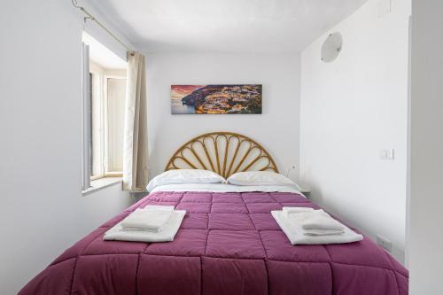 una camera da letto con un letto viola e asciugamani di Alexa & Ella House a Positano