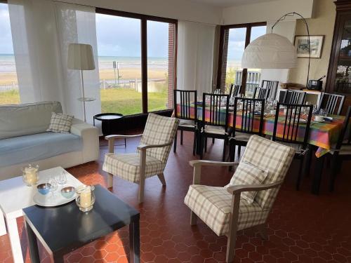 a living room with a couch and a table with chairs at Villa d'architecte - Les Pieds dans l'Eau in Ver-sur-Mer
