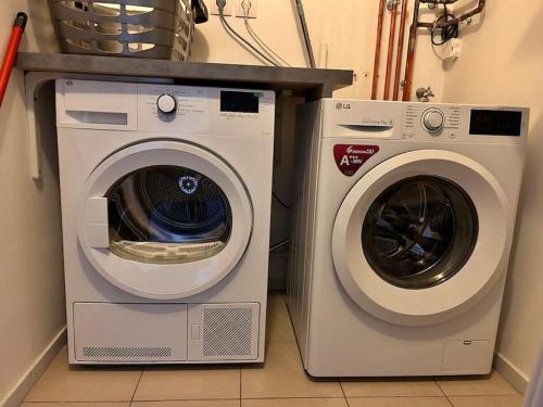 una lavatrice e un'asciugatrice sedute l'una accanto all'altra di Apart 85 m2 proche de paris stade de France parking free a Groslay