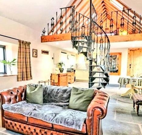 a living room with a couch and a spiral staircase at Stable Lodge in Berwick-Upon-Tweed