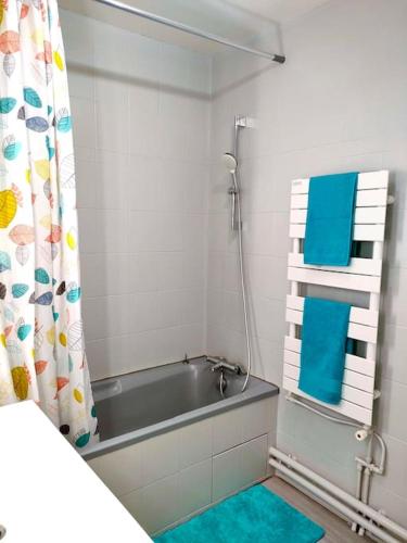 La salle de bains est pourvue d'une baignoire et de serviettes bleues. dans l'établissement Apart 85 m2 proche de paris stade de France parking free, à Groslay