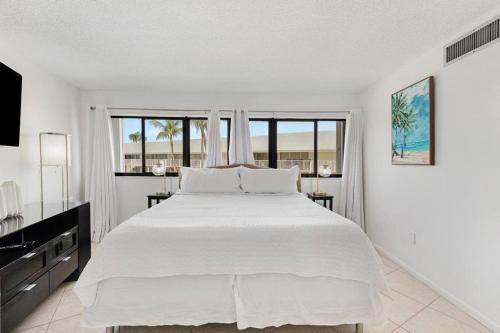 a white bedroom with a large bed and windows at Overlooking Marina/Ocean view & FREE GOLF CART in Key Largo