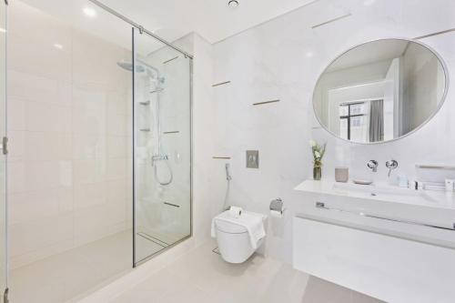 a white bathroom with a shower and a toilet and a sink at Silkhaus new 1BDR with Private beach in Dubai