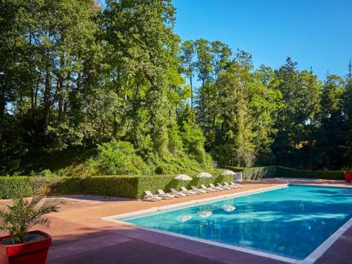einen Pool mit Sonnenschirmen und Stühlen im Hof in der Unterkunft Bungalow de 2 chambres avec piscine partagee a Saint Cheron in Saint-Chéron
