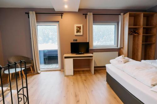 a bedroom with a bed and a desk with a television at The Art and Sporthotel in Innsbruck